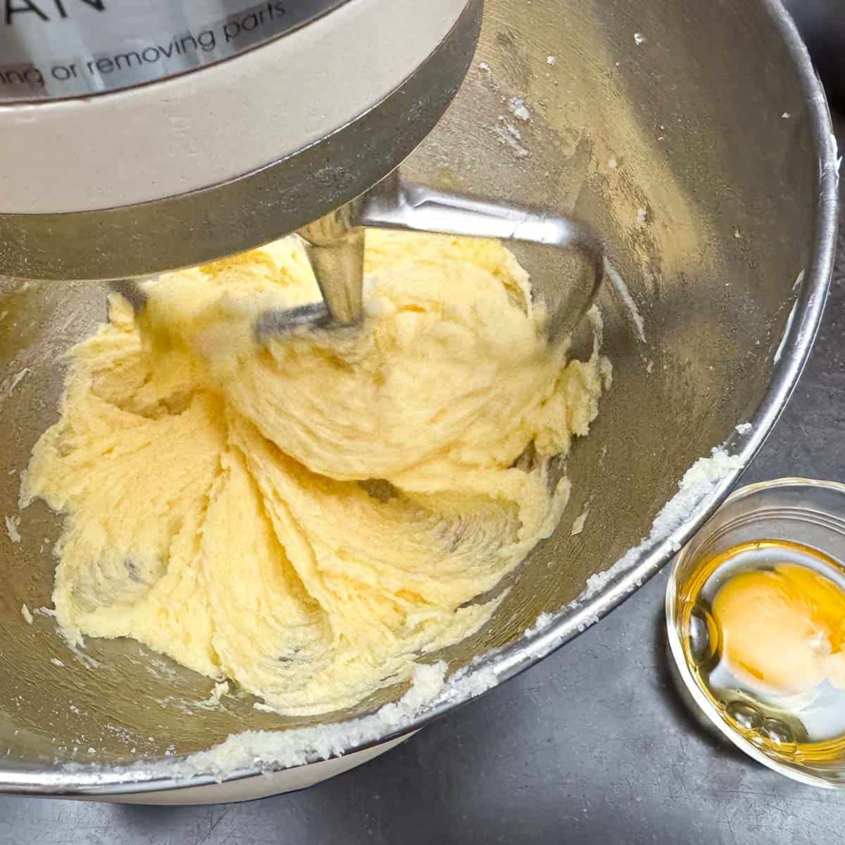 Adding eggs one at a time into the mixing bowl.