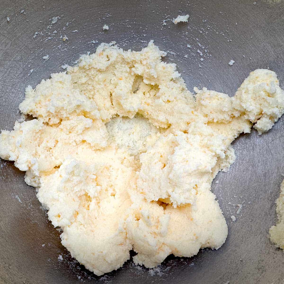 In the mixer bowl is the creamed butter and the orange zest sugar that has been mixed for three minutes. Still looks grainy because of the amount of sugar to butter.