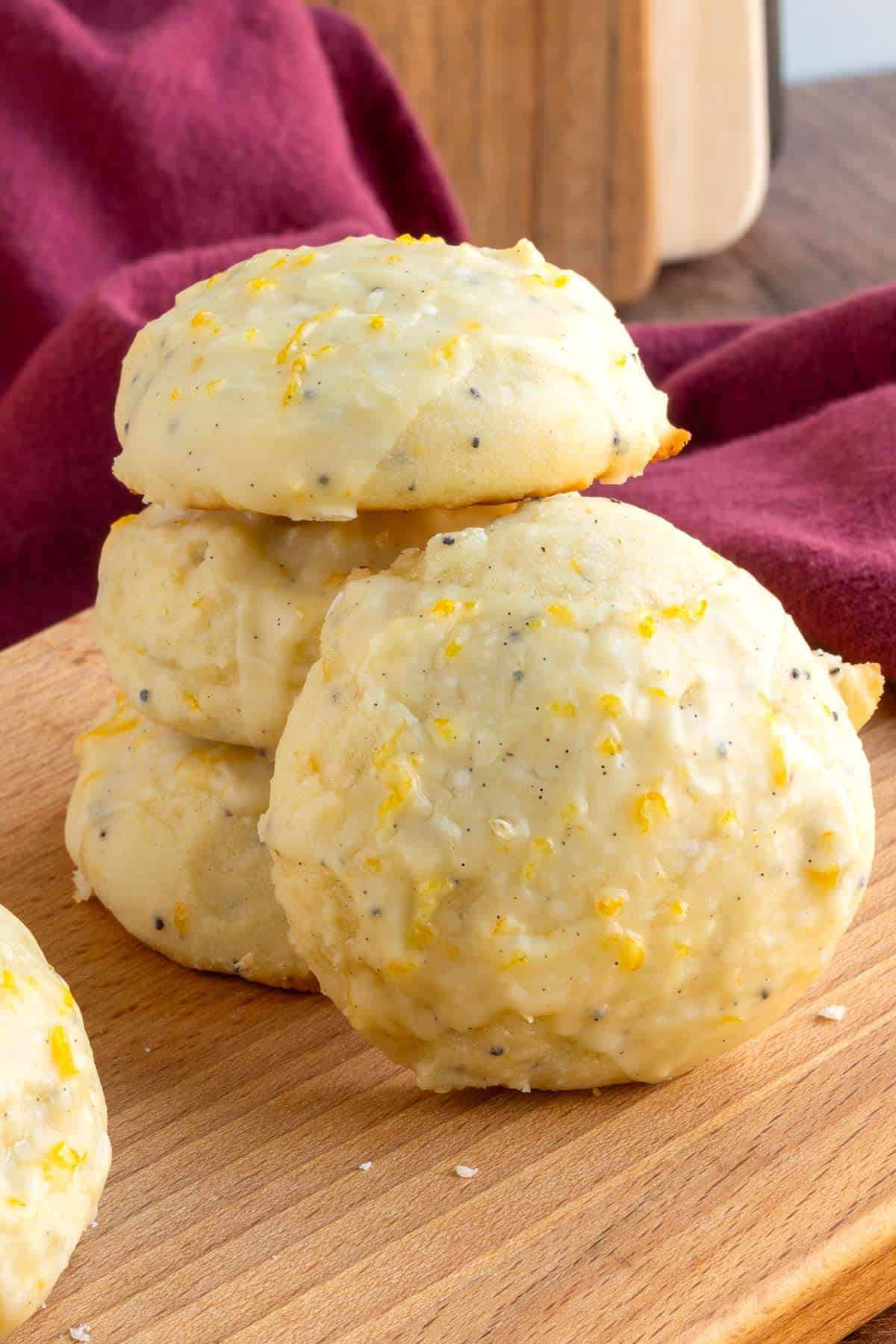 Front and side view of finished Glazed Ricotta Orange Cookies, on a wooden board.