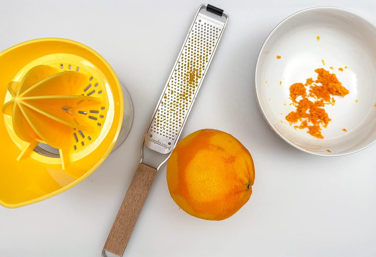 Zesting and juicing an orange on a cutting board.