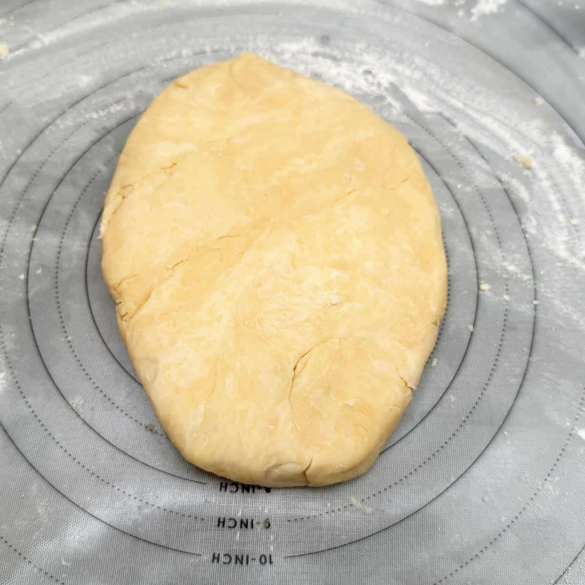 Cookie dough that has been kneaded and shaped into an oval on a pastry mat.