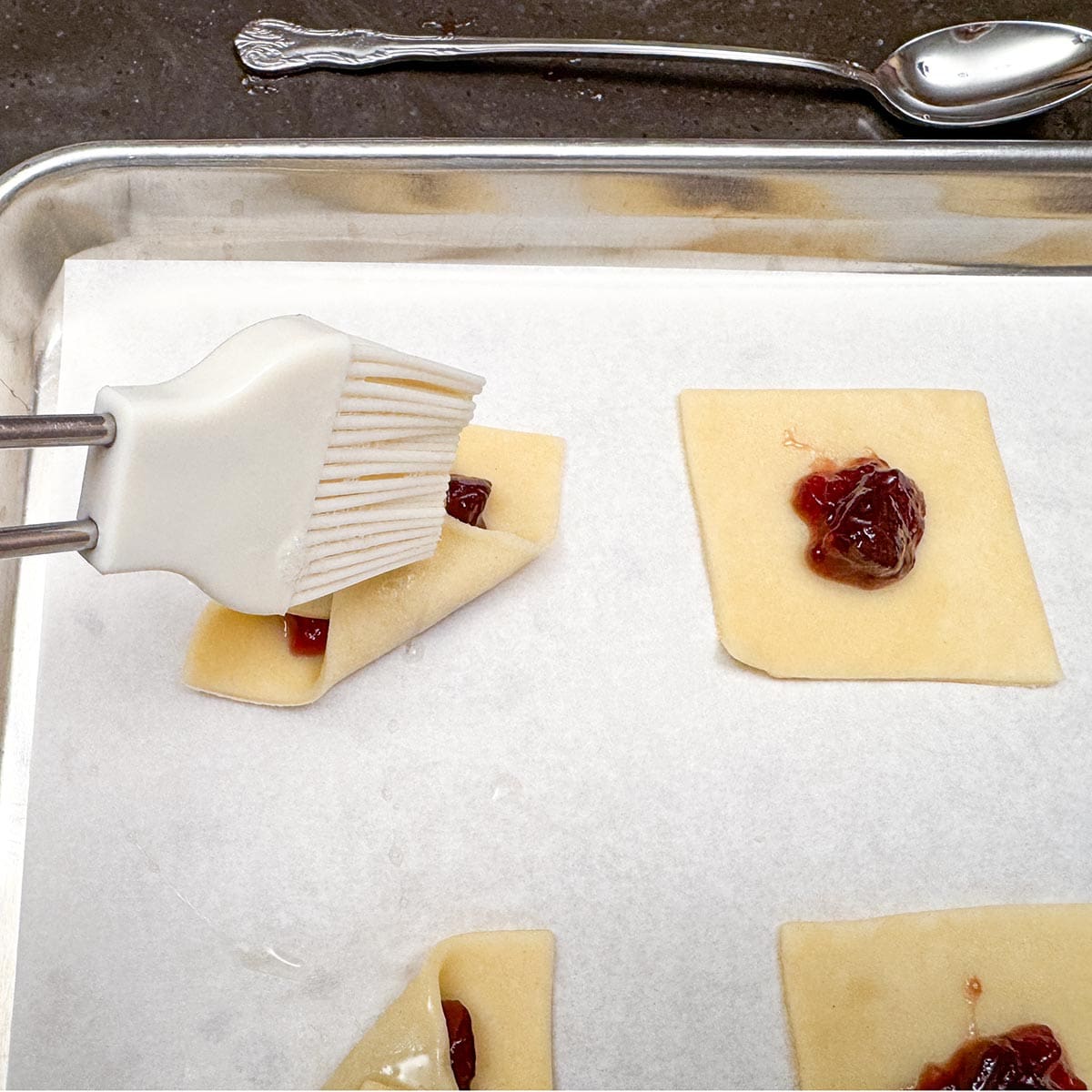 Brushing the white egg wash on the top seams to prevent the corners from opening up.
