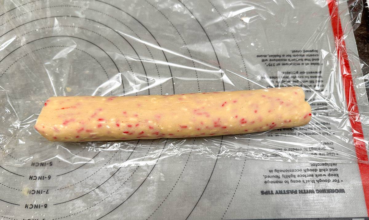 Wrapping a 9 inch sprinkle cookie log roll on a pastry mat.