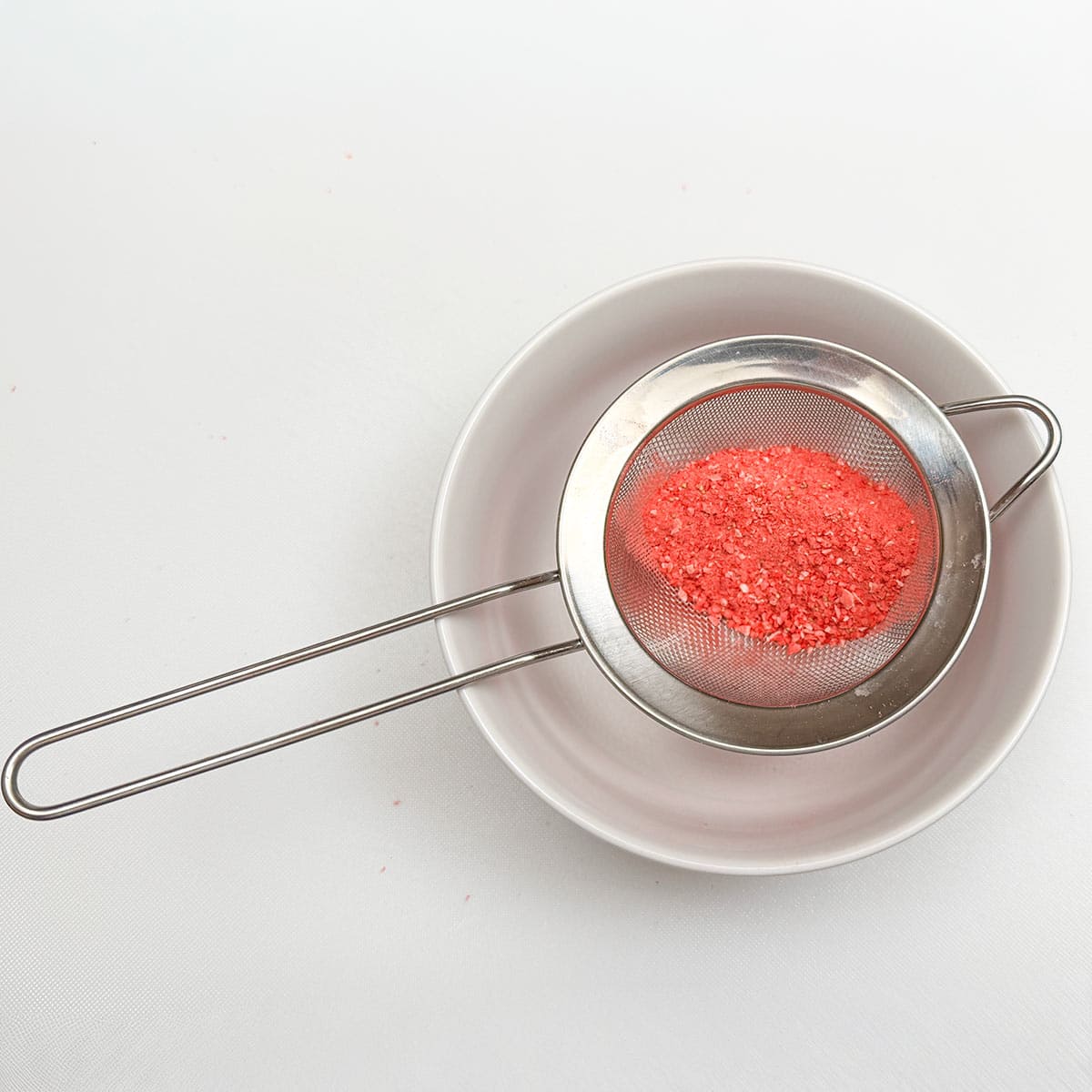 Sifting the crushed freeze-dried strawberries through a sifter.