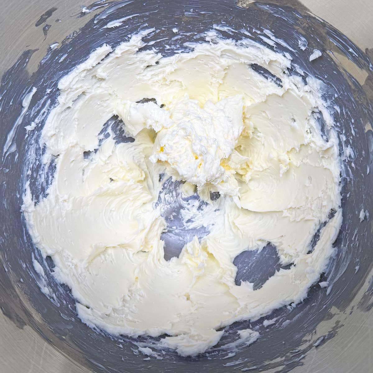 Cubed butter that has been creamed in a mixing bowl.
