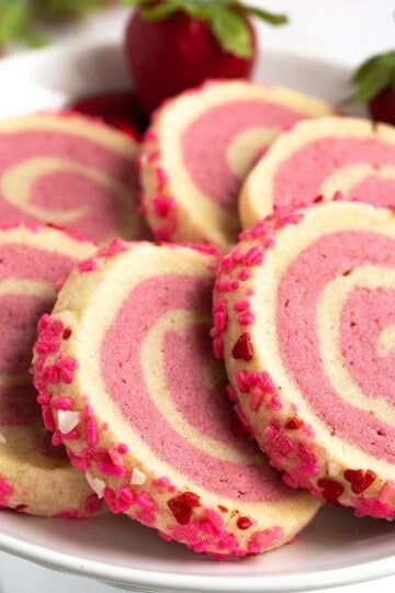 Strawberry and vanilla pinwheel sugar cookies from view of the nice pinwheel of the two color cookie dough and the jimmies on the side.