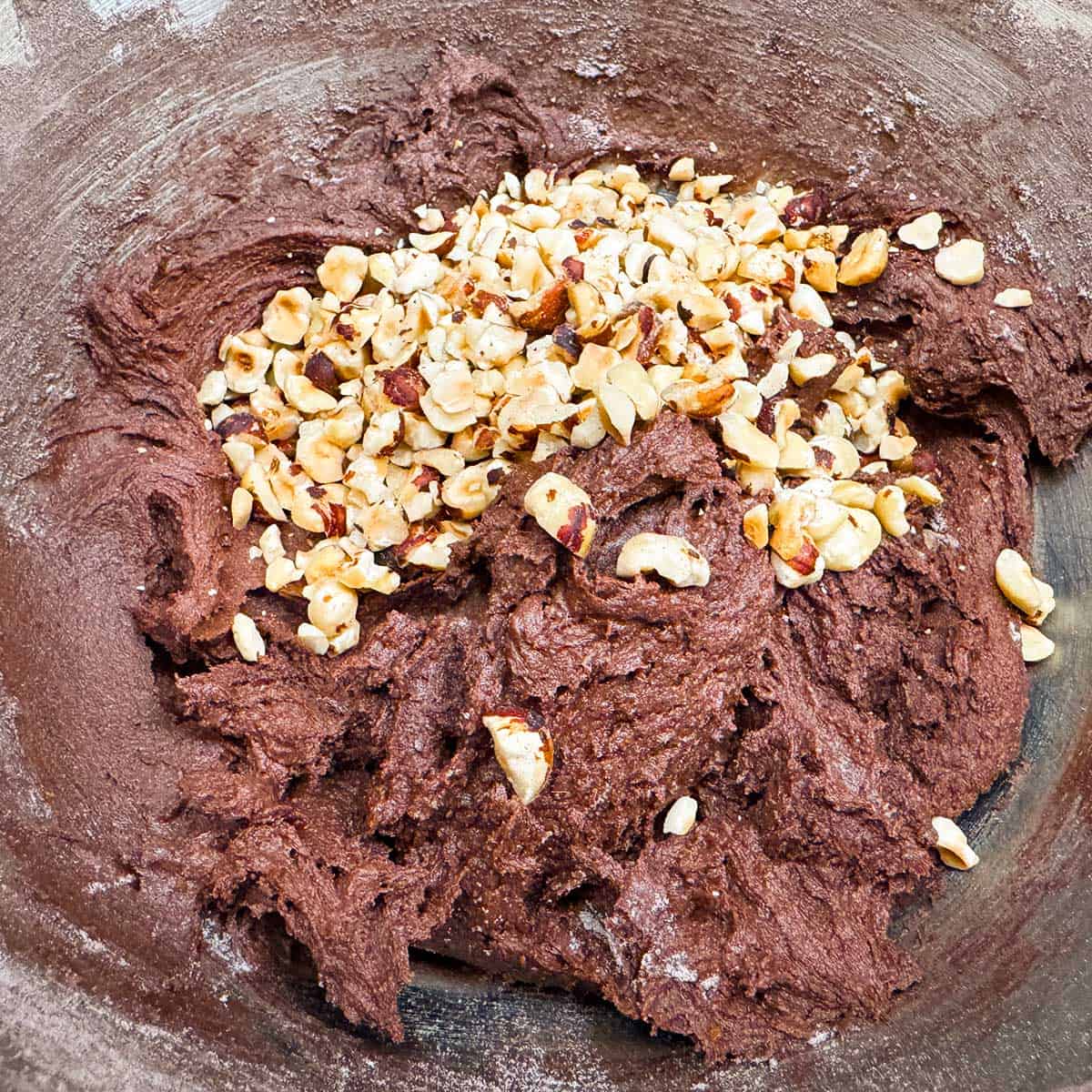 Adding chopped hazelnuts to the completed cookie dough.