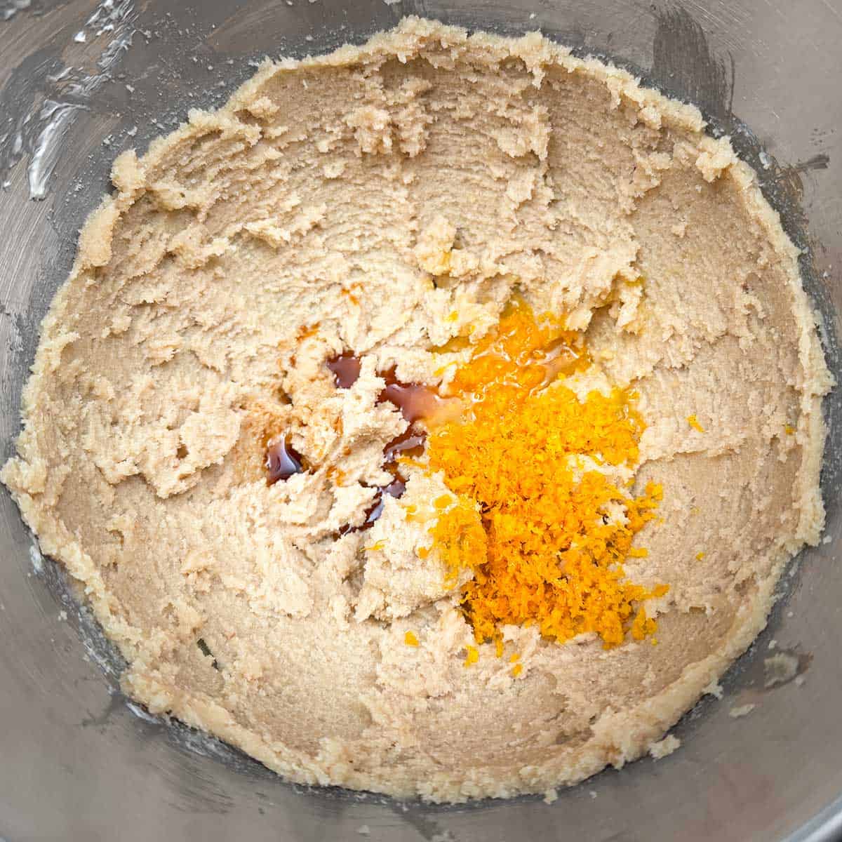 Adding the vanilla extract and the orange zest and juice to the butter-sugar mixture.
