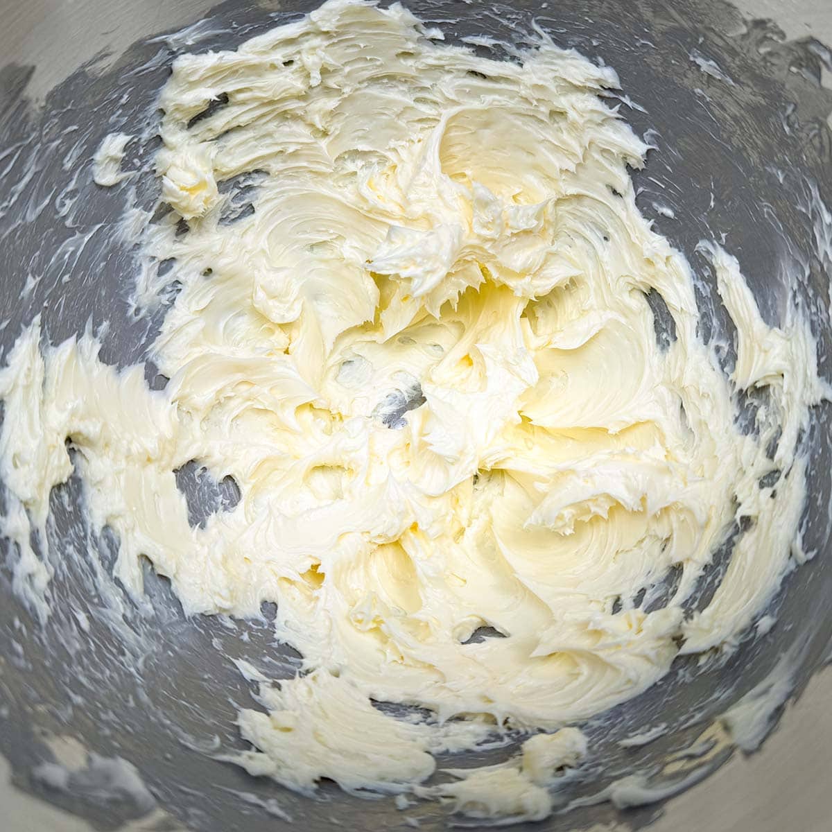 Creamed butter in the mixer bowl with soft butter peaks.