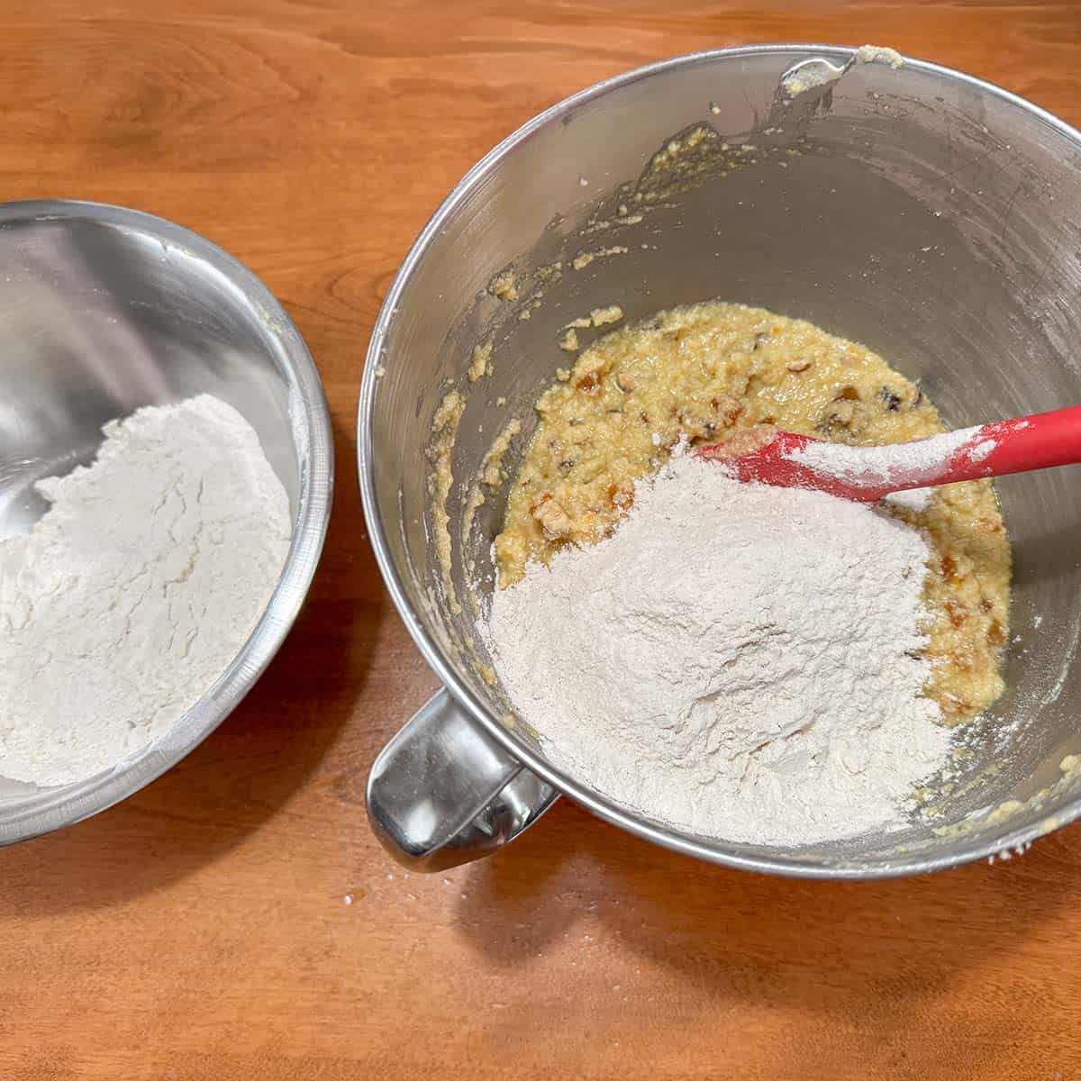 Adding flour mixture into the wet cookie dough using a solid spatula.