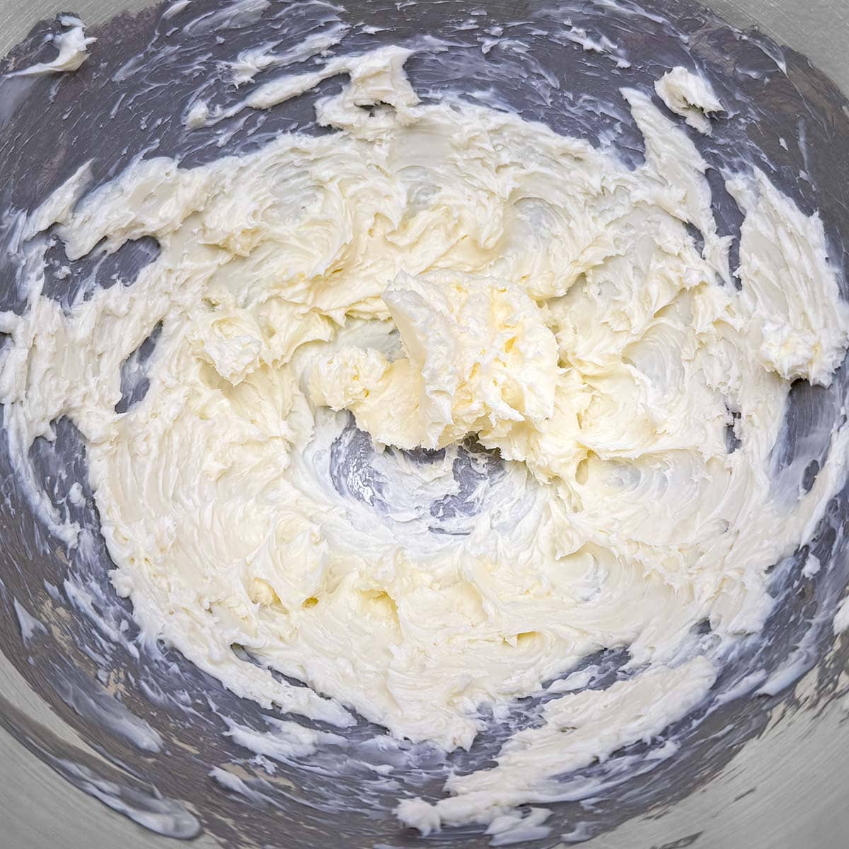 Creamed butter with soft peaks in a mixer bowl.