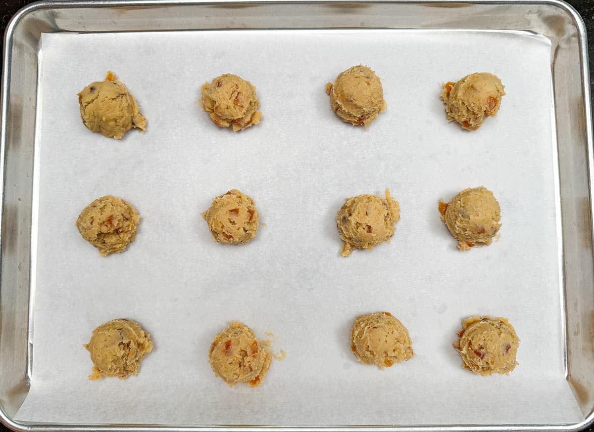 Apricot with orange and hazelnut cookies scooped out onto a lined sheet pan.