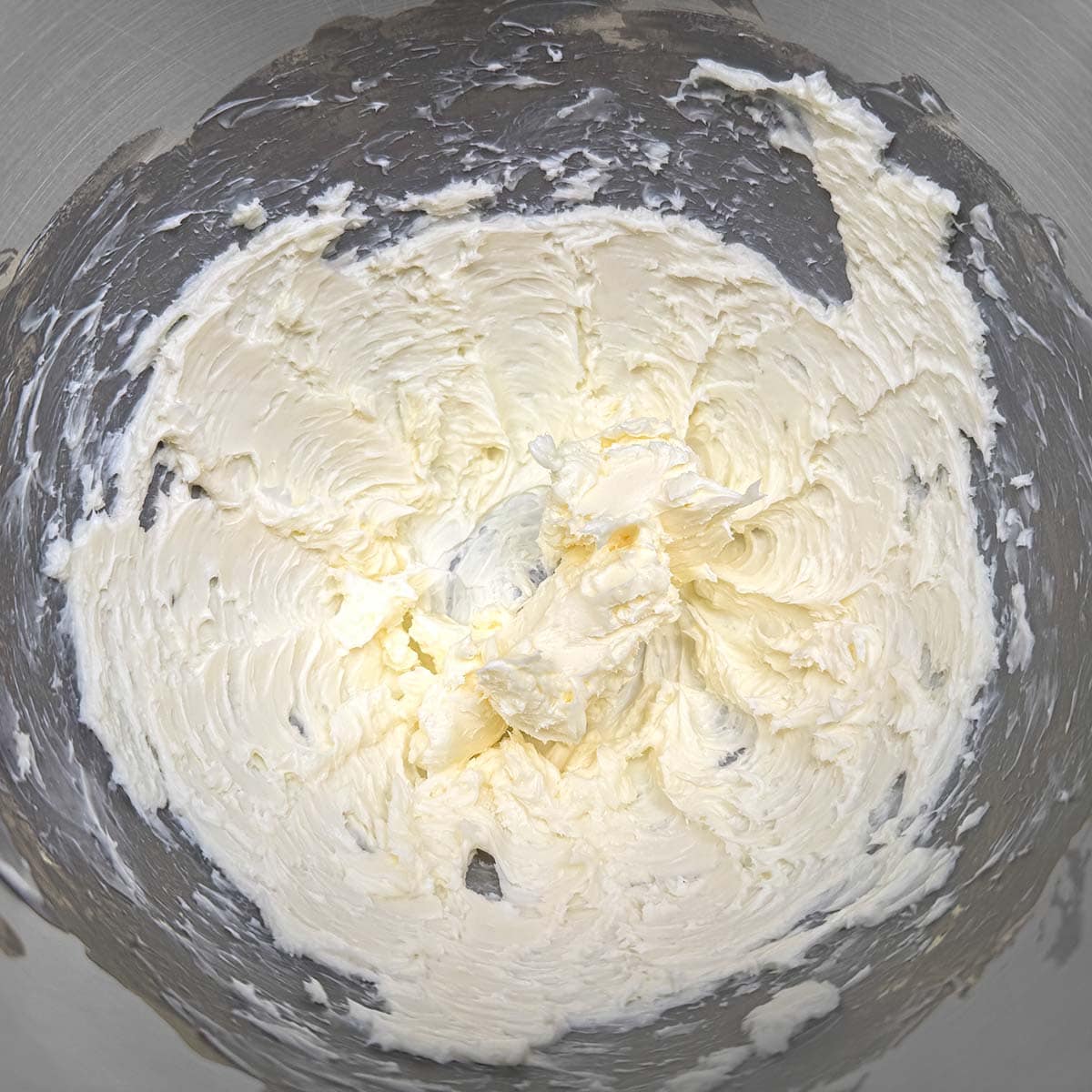 Creamed butter with soft peaks in a mixer bowl.