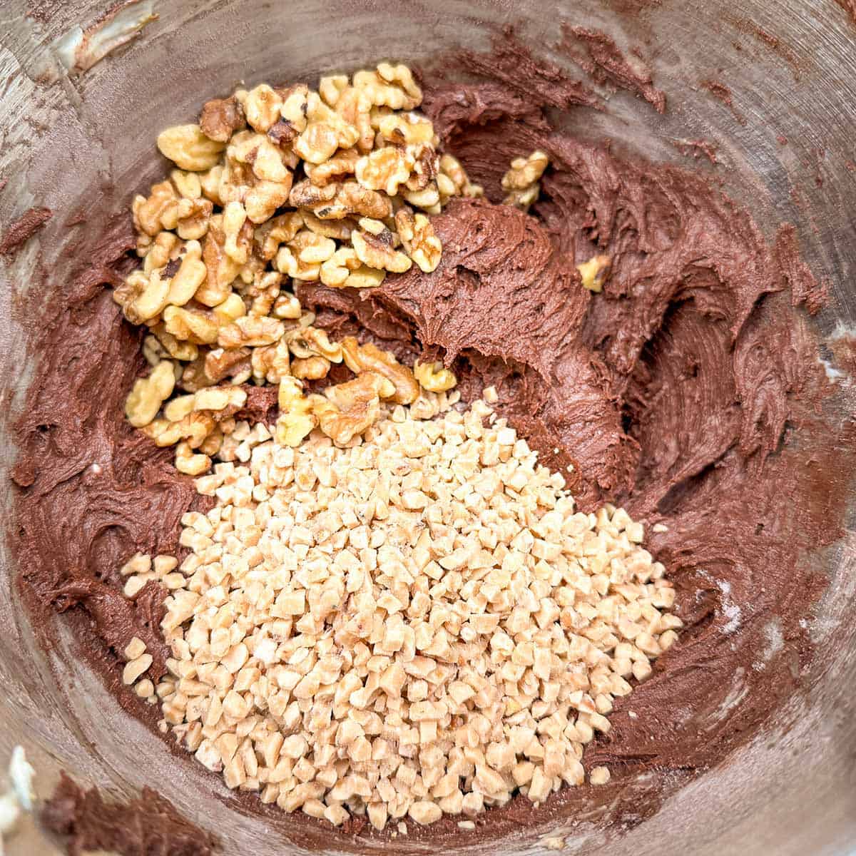Adding the toffee bits and the chopped walnuts to the chocolate cookies dough.