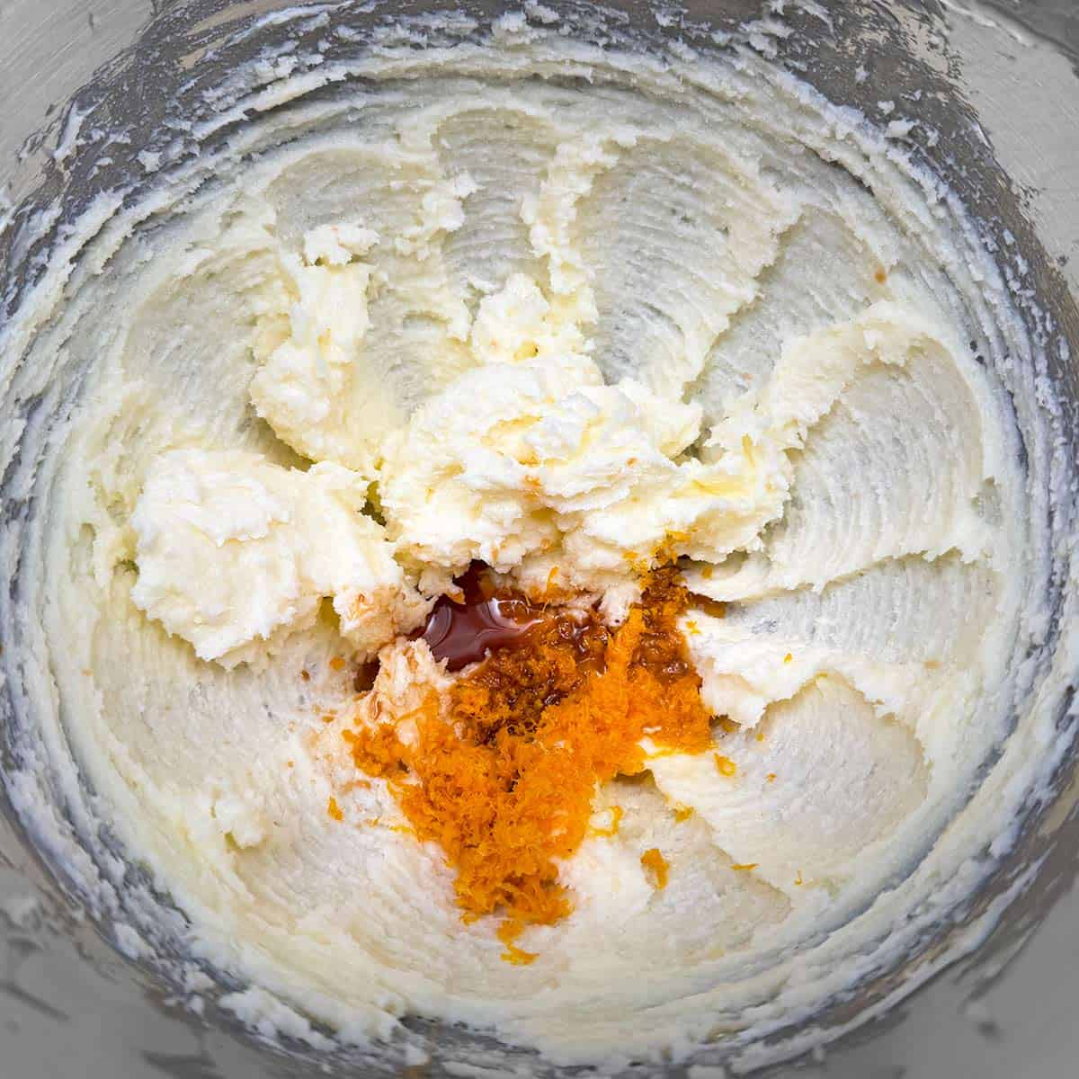 Adding orange juice, orange zest, and vanilla to the butter-sugar mixture.