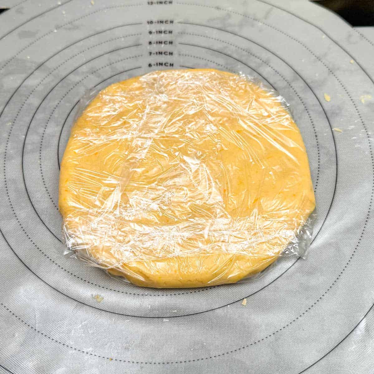 Cookie dough disk that is wrapped in plastic wrap ready to be chilled.