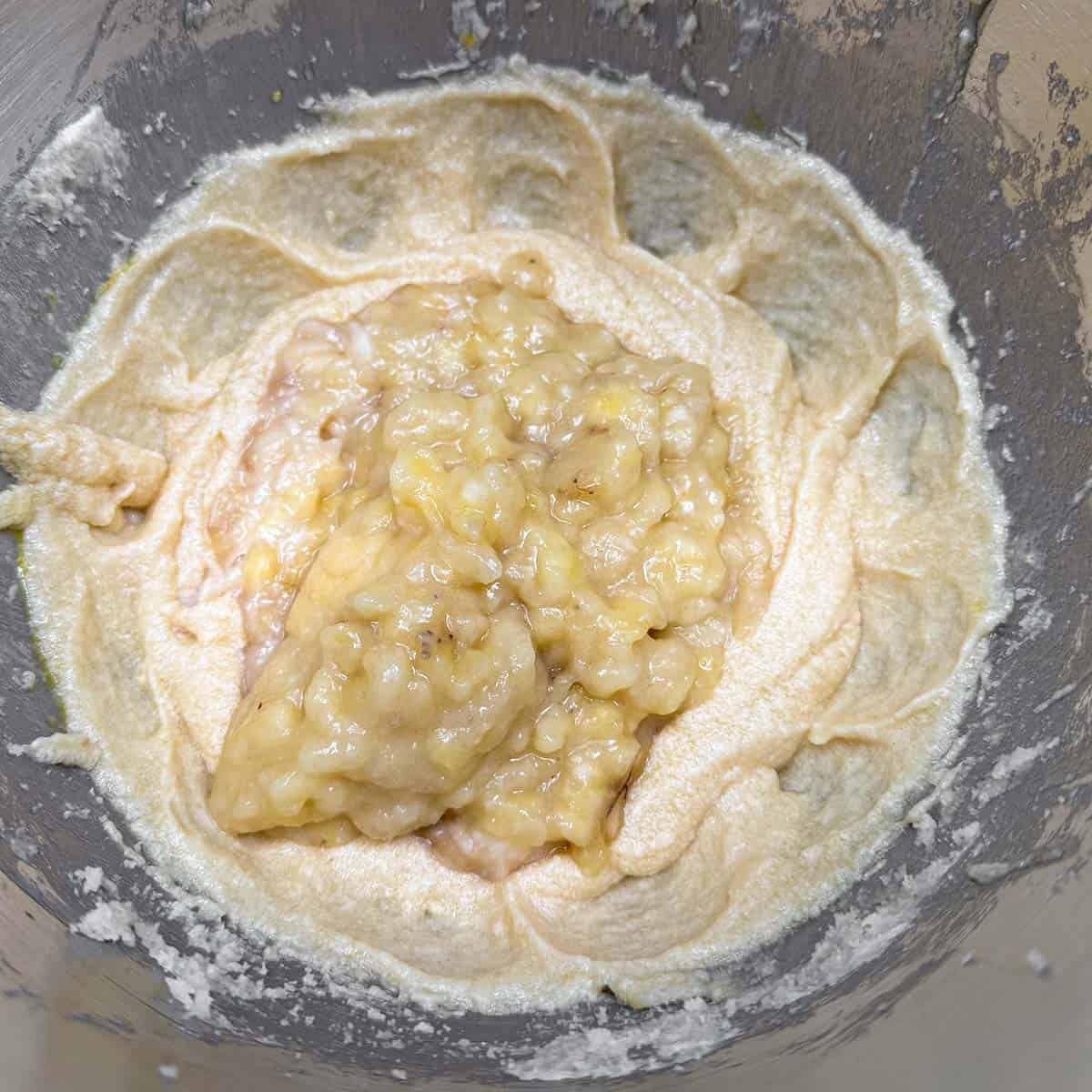 Adding the smashed ripe bananas to the wet cookie dough.