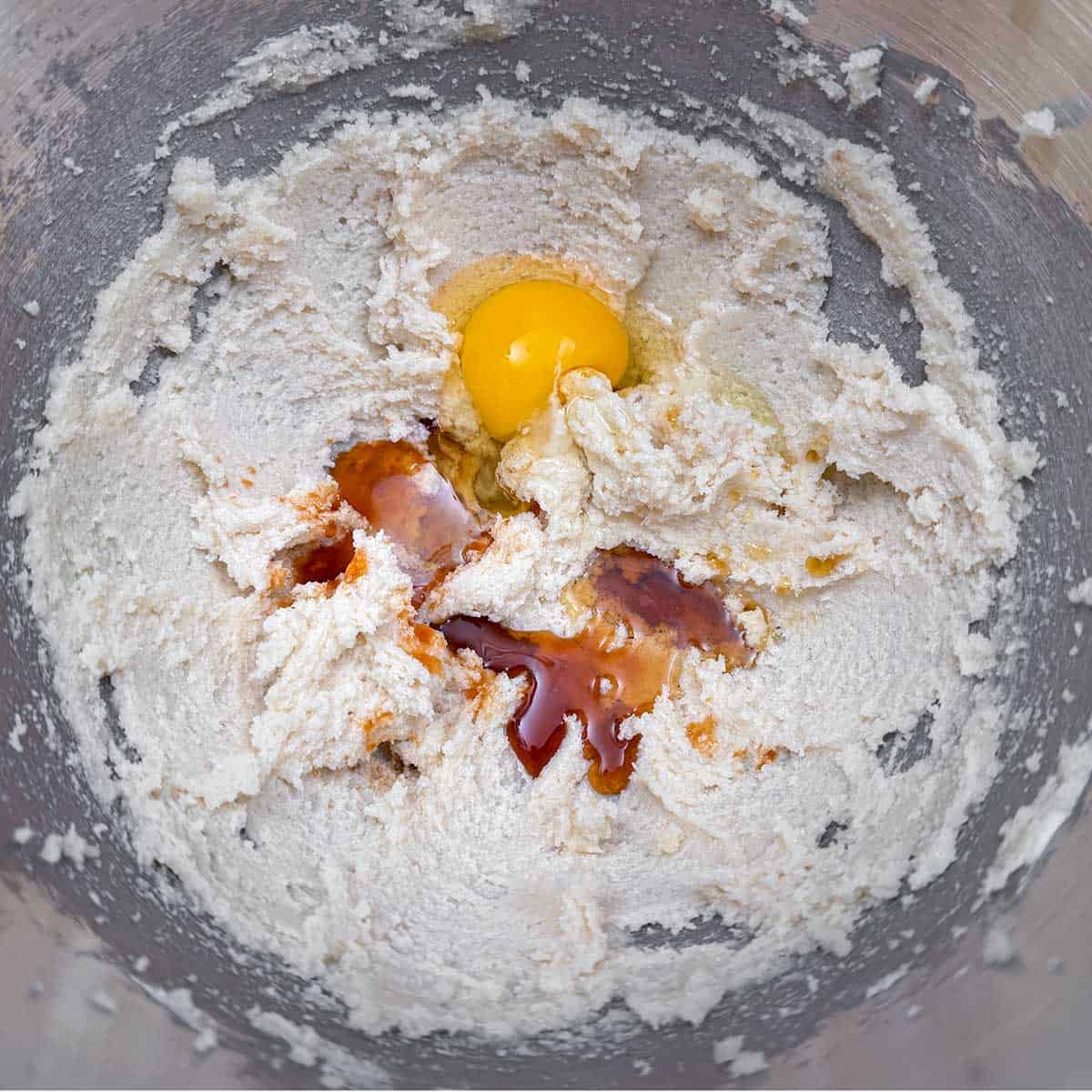 Adding the vanilla extract, maple syrup, and the first of 2 eggs into the butter-sugar mixture.