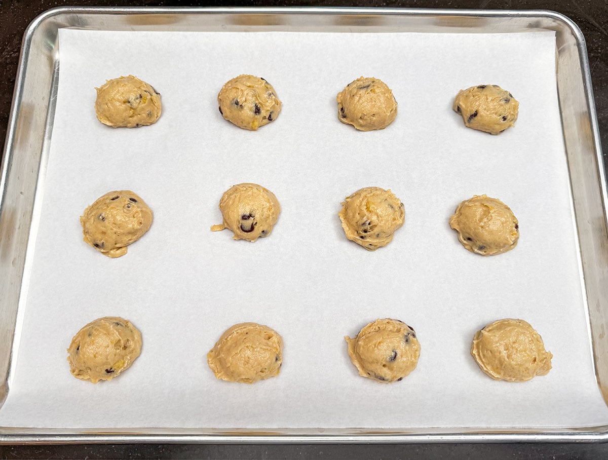 Soft banana bread cookie dough, scooped onto a parchment-lined sheet pan.