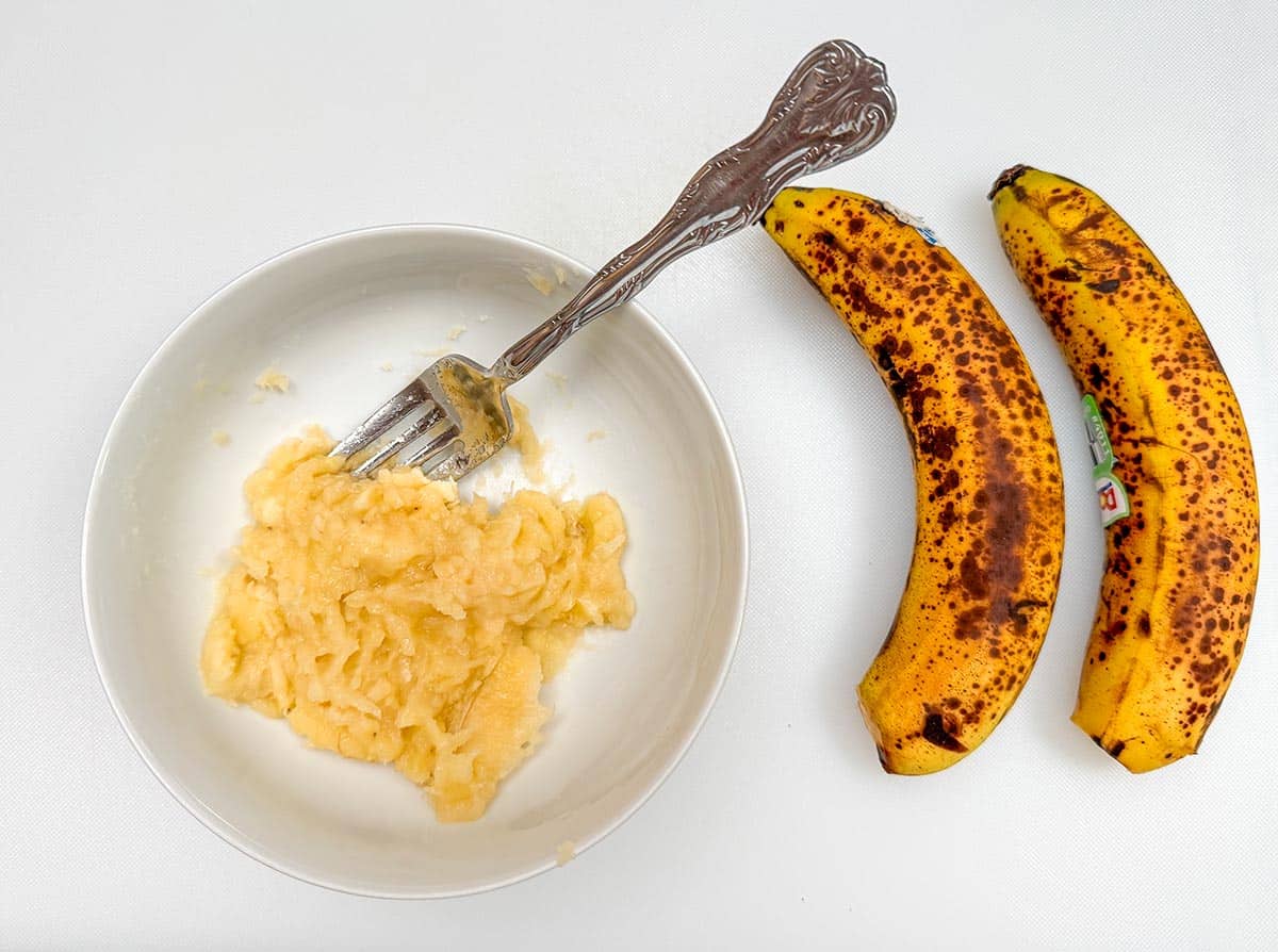 Ripe bananas being smashed with a fork.