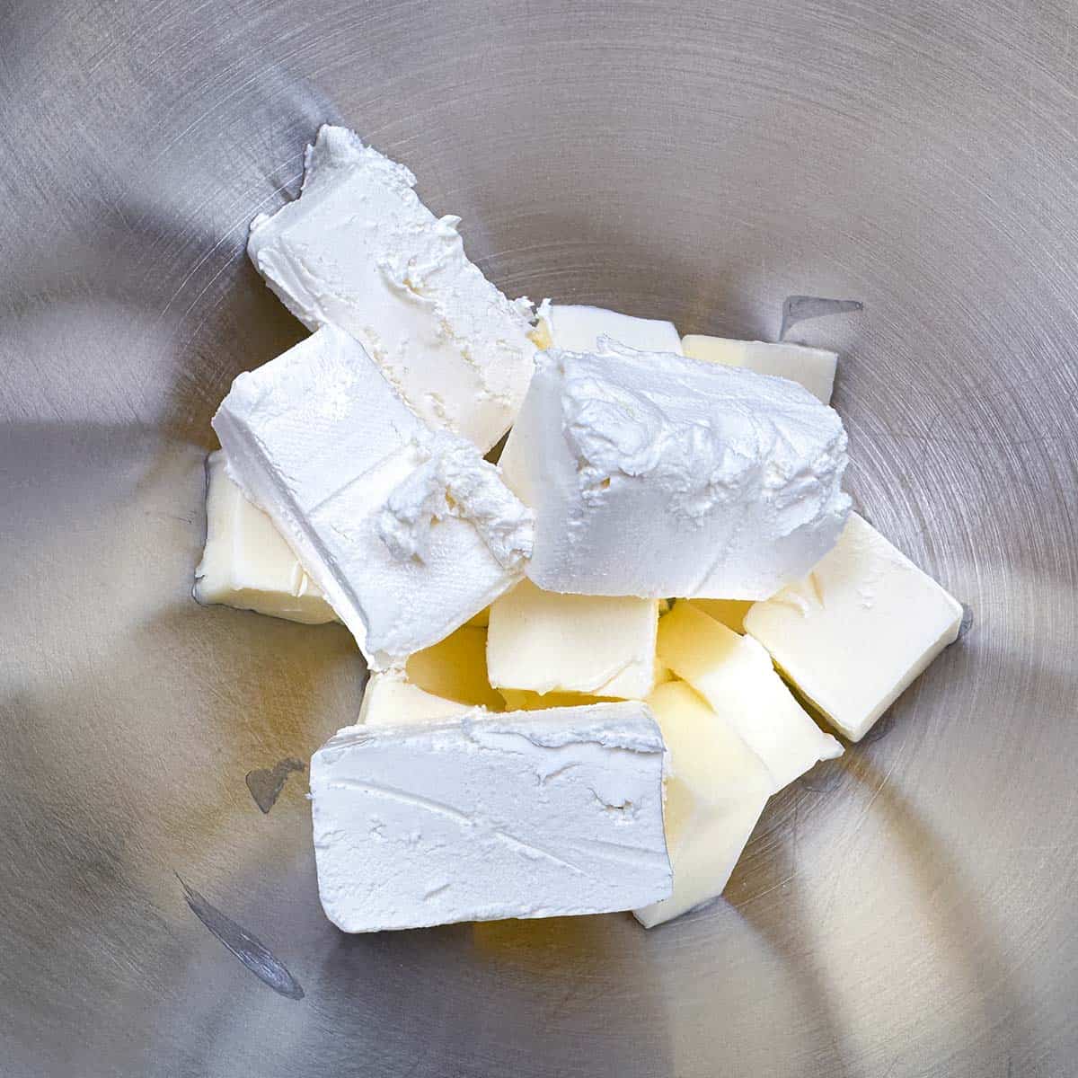 Butter and cream cheese cut up in a mixer bowl.