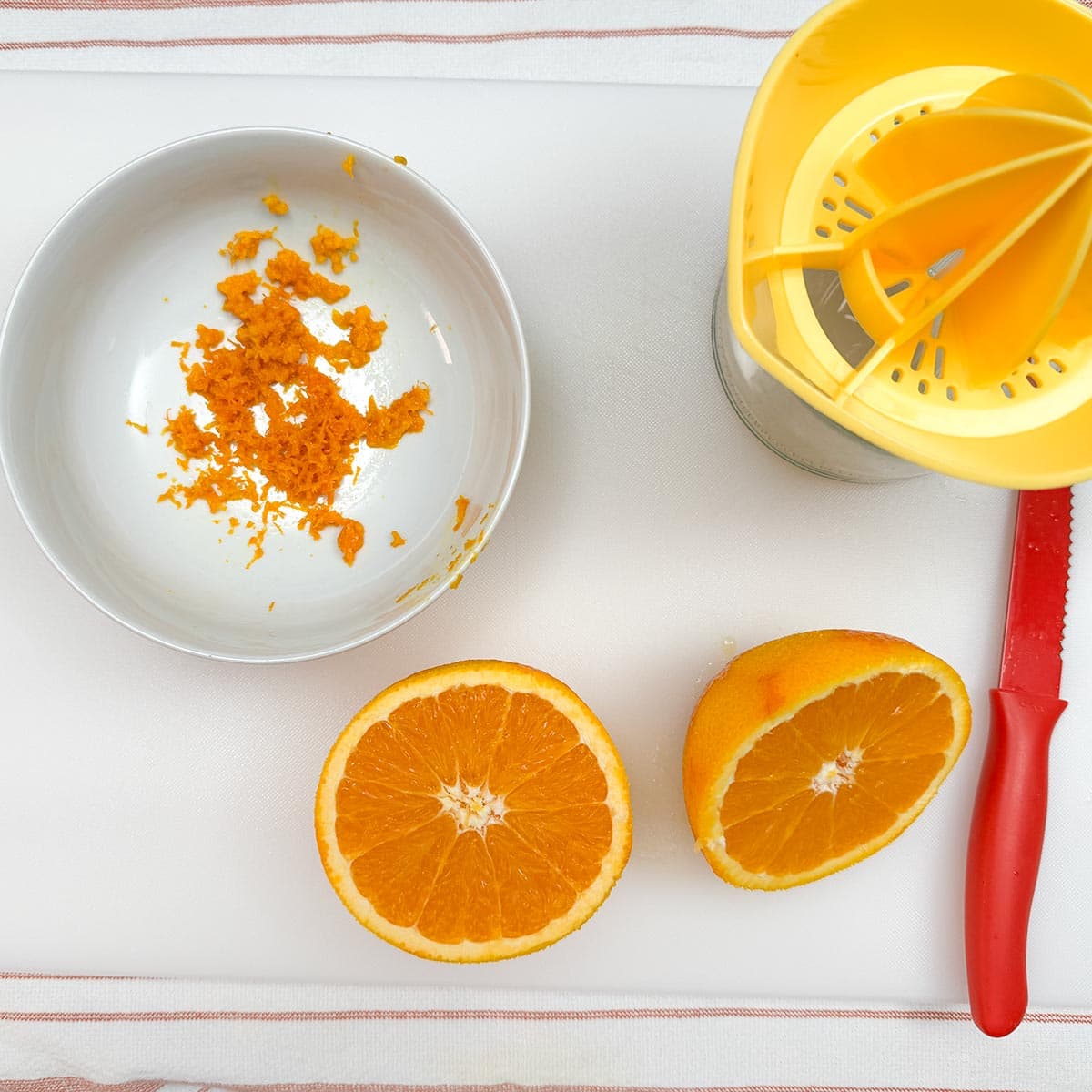 Zesting and juicing an orange on a cutting board.