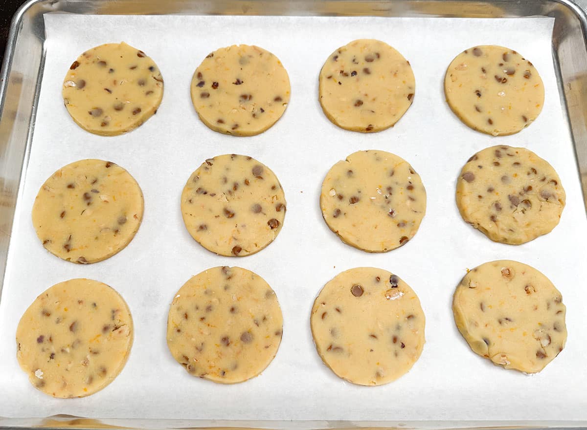 Twelve cutout cookies on a parchment-lined sheet pan ready for the oven.