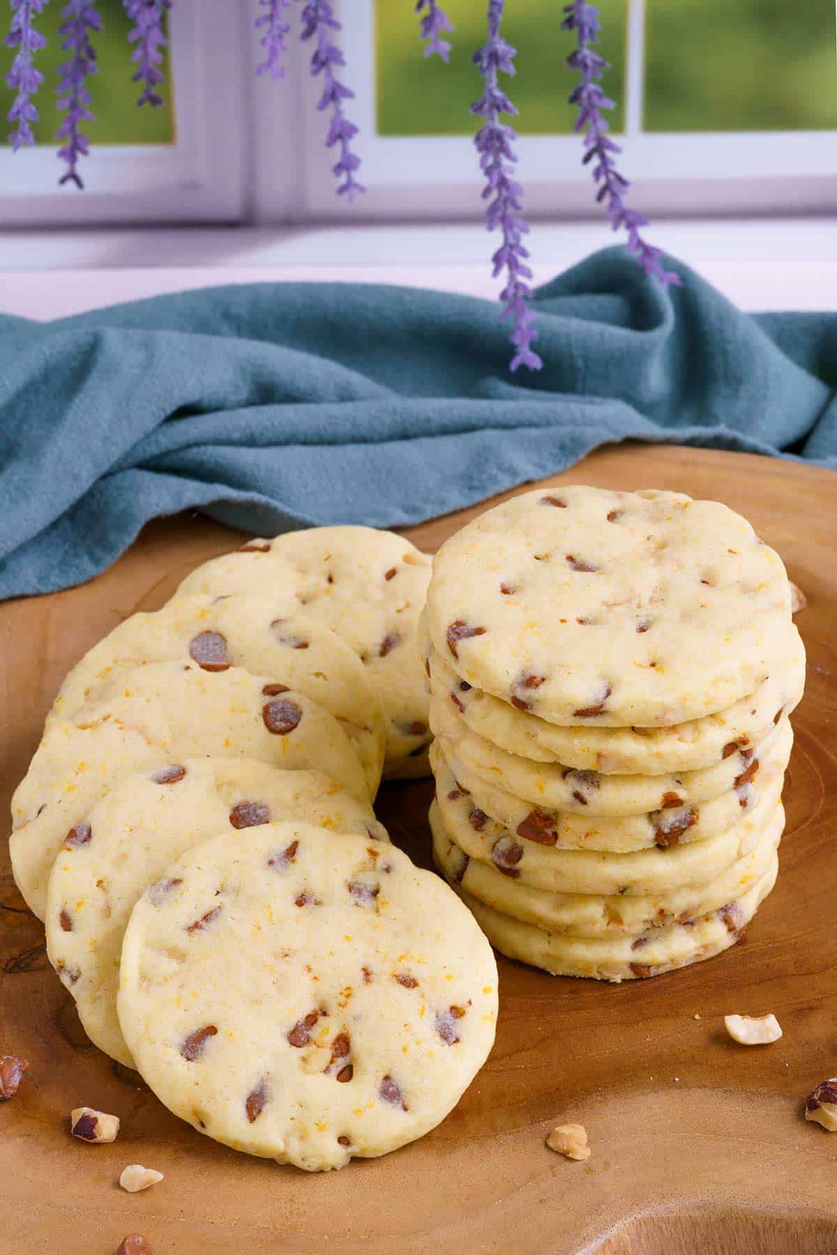 Orange cinnamon chip sugar cookies on a wooden board stacked with cookies laying around the stack.
