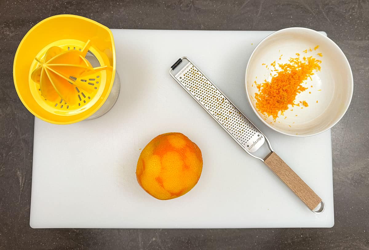 A bowl with orange zest and getting ready to juice the orange.
