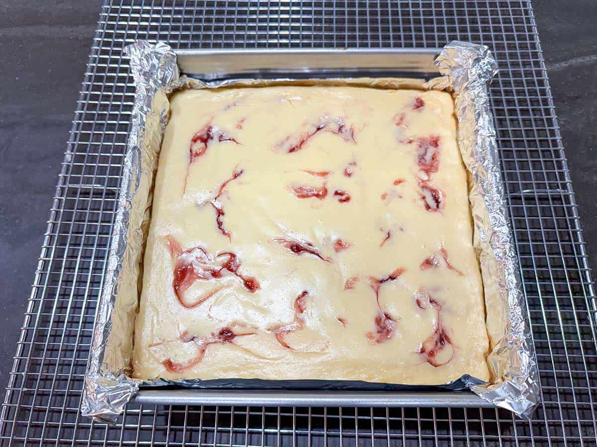 Baked strawberry key lime cheesecake in the pan cooling on the rack.