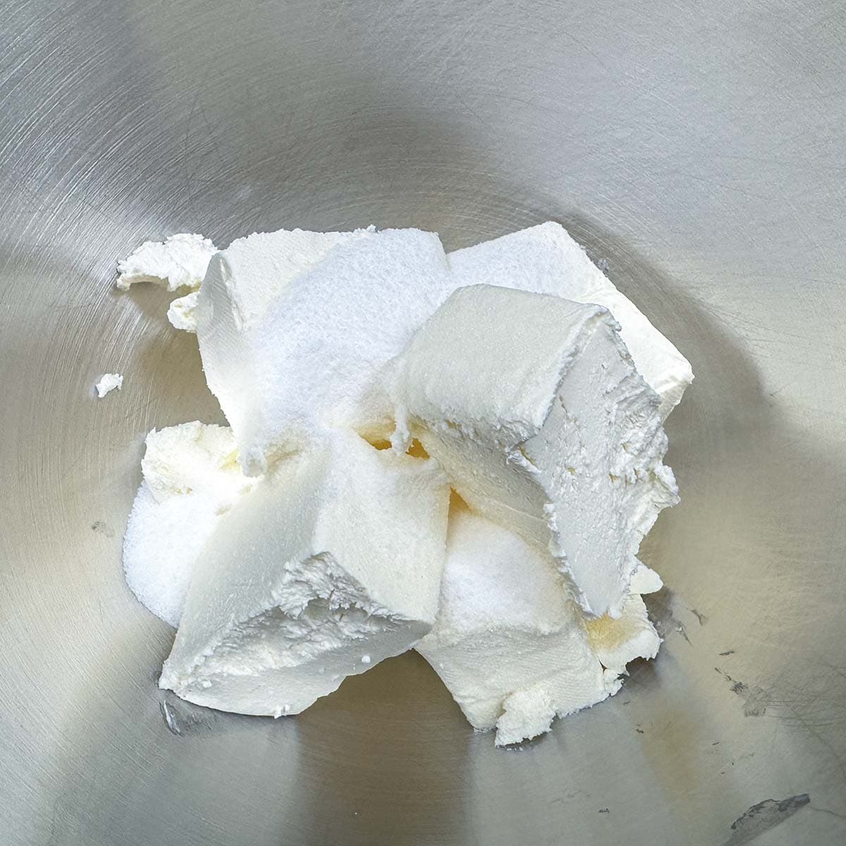 Adding the cream cheese and sugar to a mixer bowl.