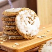 Maple cinnamon iced oatmeal cookies stacked with on front view leaning against the stack of cookies.