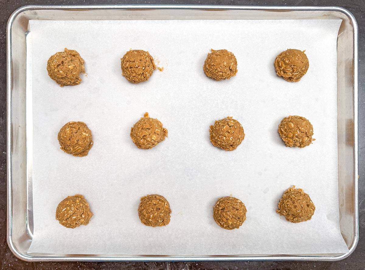Scooped chilled cookie mixture on a parchment lined cookie sheet pan.