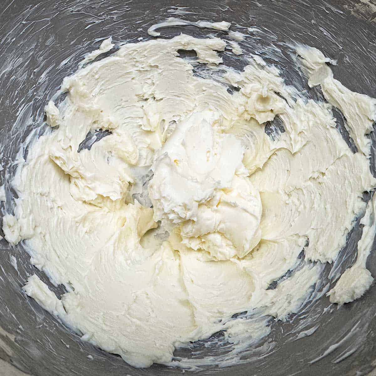 Creamed butter with soft peaks in a mixer bowl.