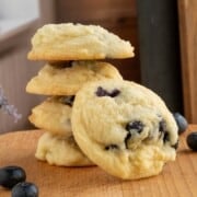 Fresh blueberry lemon maple cookies in a stack with one showing the front side with plump blueberries showing through.