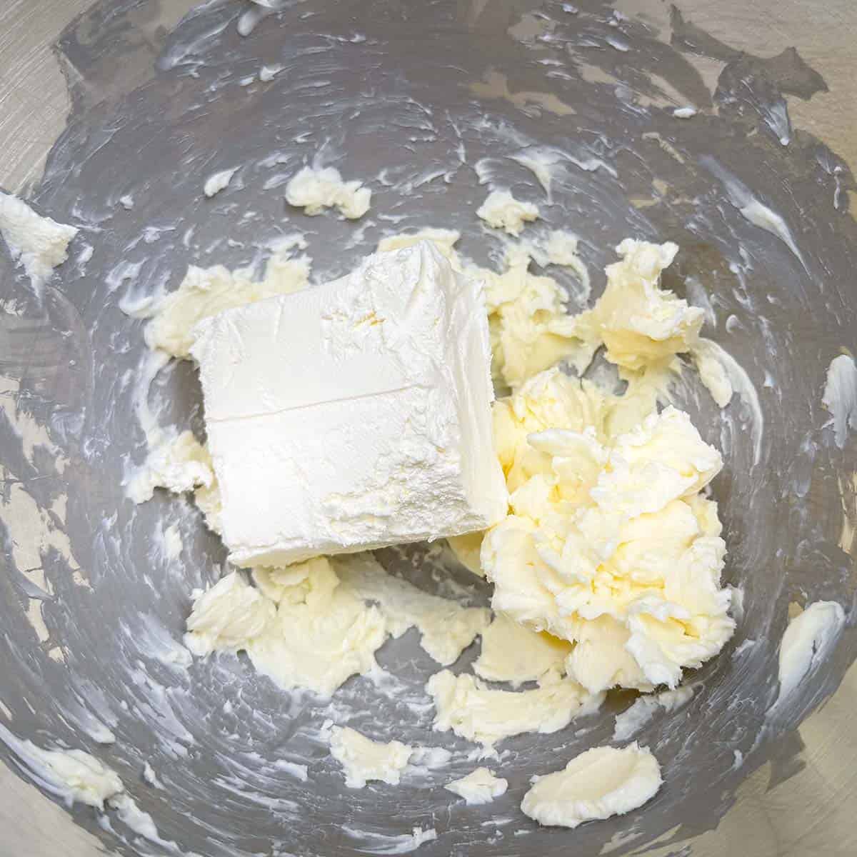 A block of cream cheese on top of creamed butter.