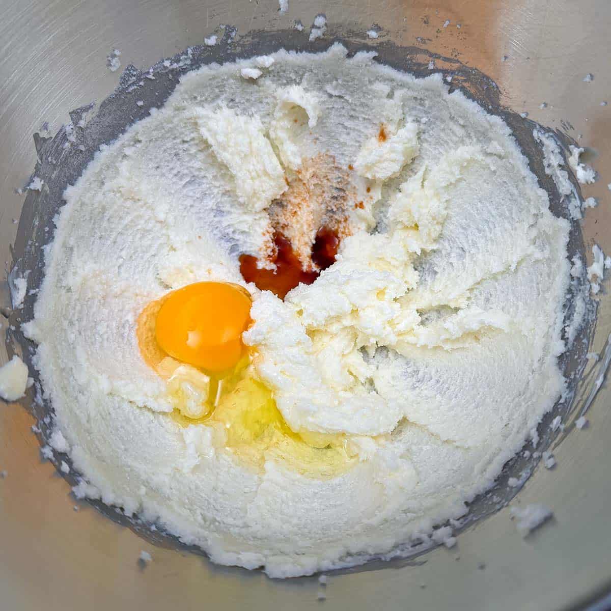 Butter sugar mixture with an egg and vanilla extract in a mixer bowl.
