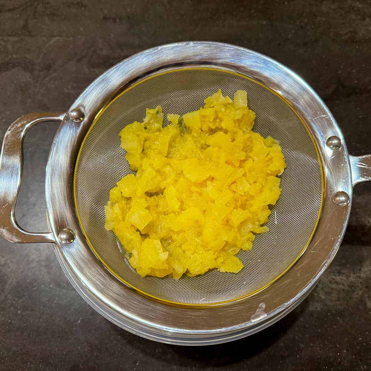 Pineapple draining in a sieve.