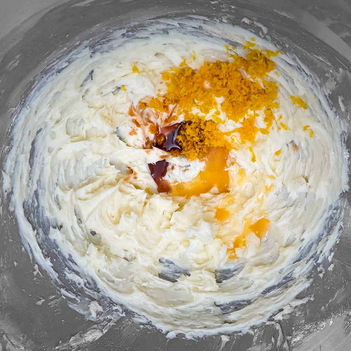 Adding orange and vanilla extract to the butter sugar mixture.