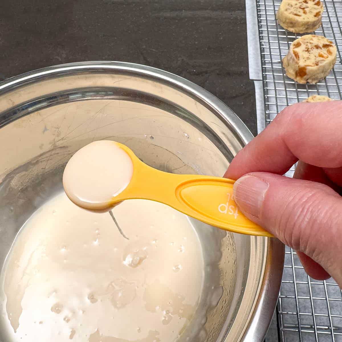 Talking a teaspoon of the honey orange glaze from the bowl.