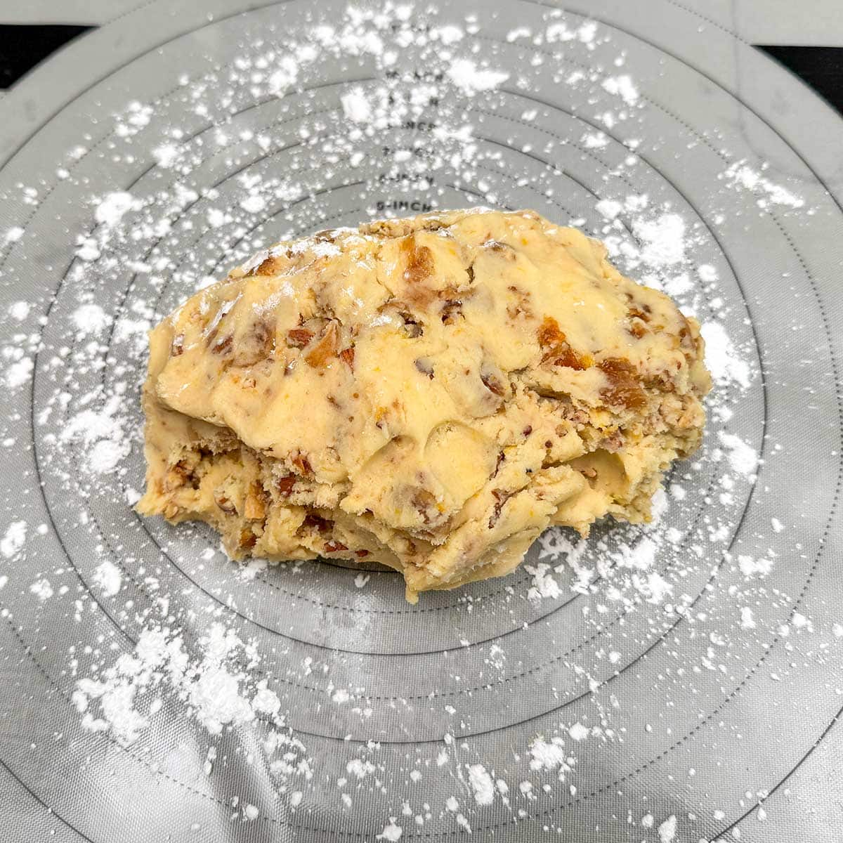Fig pecan shortbread cookie dough on a pastry sheet and sprinkled powdered sugar spread on to prevent sticking.