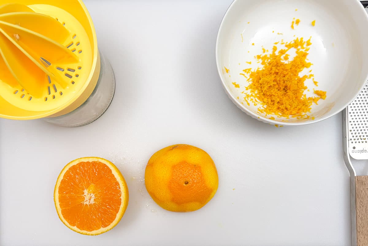 An Orange that has been zested and now is cut in half to juice.