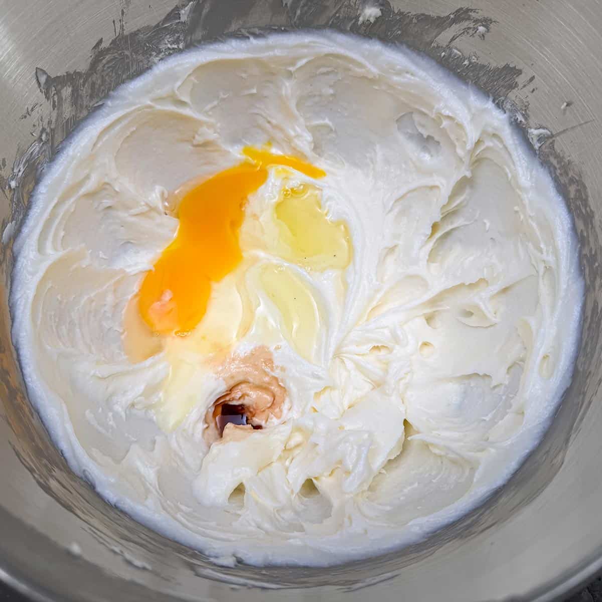Adding vanilla extract and eggs to the sugar-butter mixture.