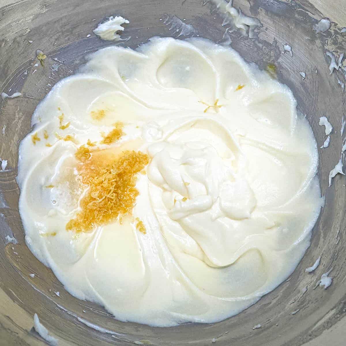 Adding the lemon zest and juice to the butter-sugar and egg mixture in a mixer bowl.