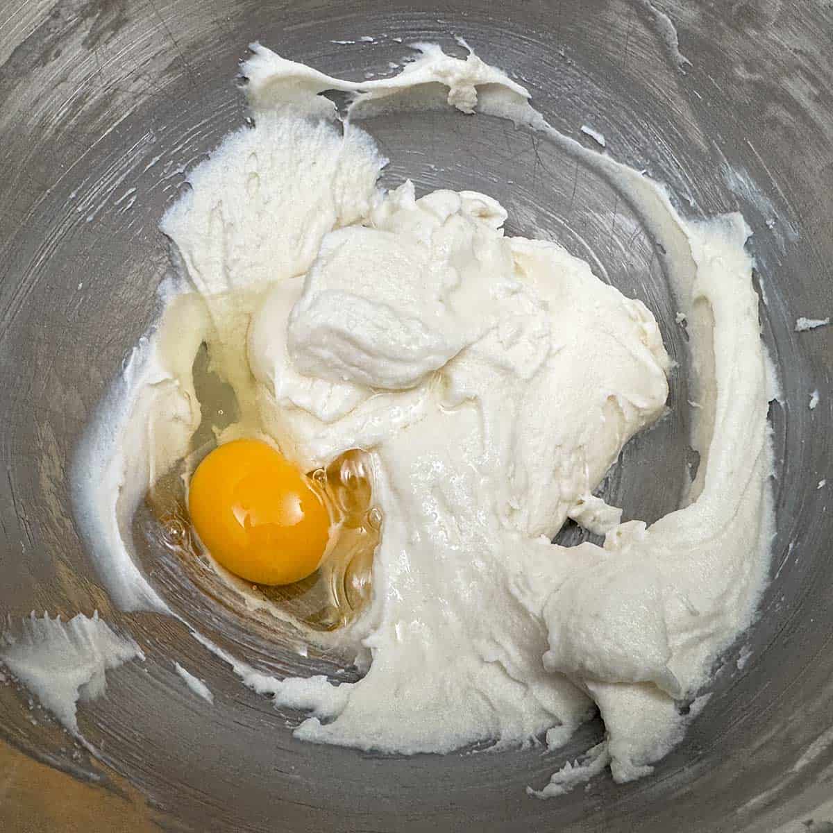 Adding the egg to the butter-cream cheese and sugar mixture.