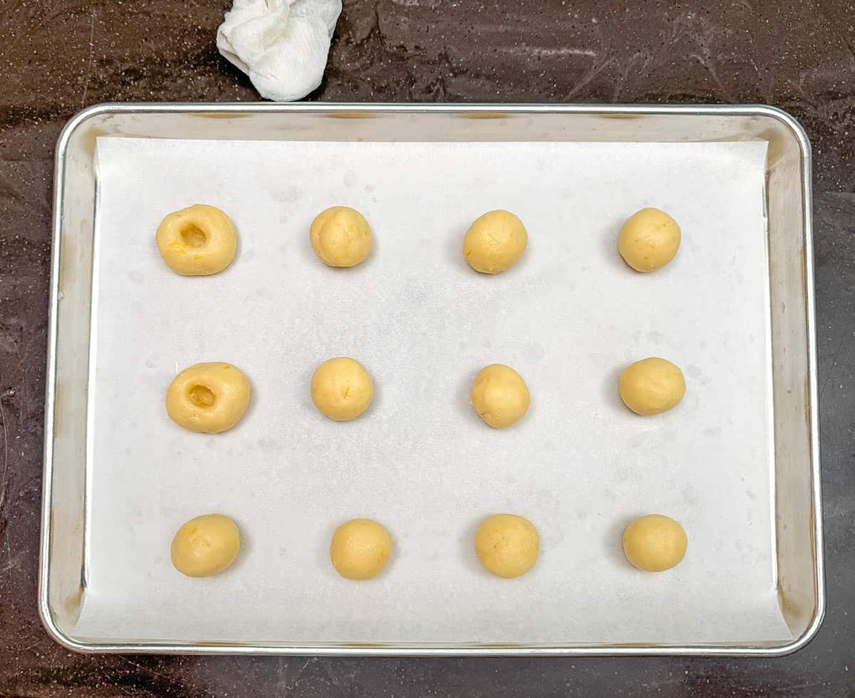 Starting to make the holes in the cookie balls and have a wet paper towel to moisten thumb between holes.