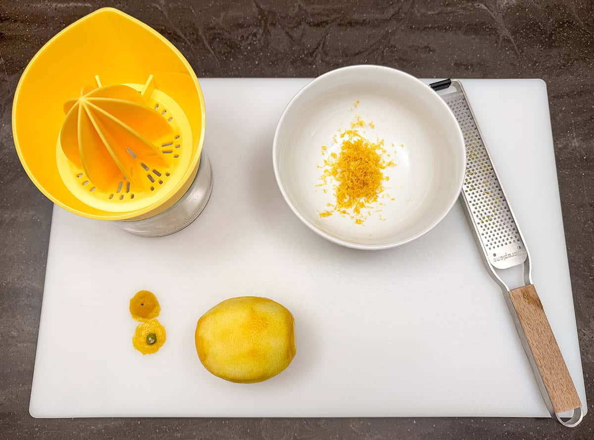 Zesting and juicing a lemon on a cutting board.