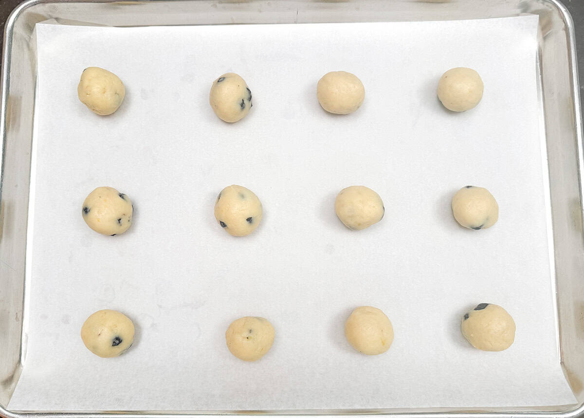 Making 12 round balls of cookie dough and placing on a parchment-lined sheet pan.