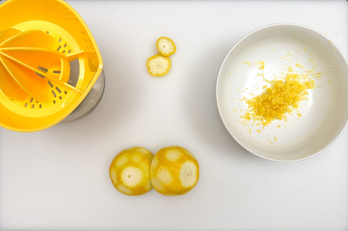 Zesting an juicing a lemon on a cutting board.