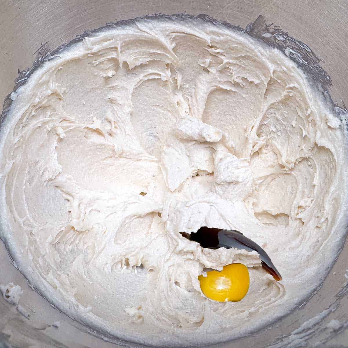 Adding an egg and vanilla extract into the butter-sugar mixture.